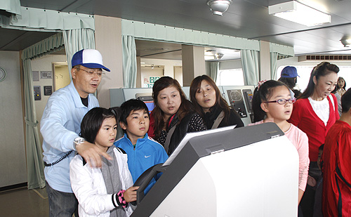 ばら積み貨物船ブリッジで熱心にスタッフの説明を聞く参加された方々